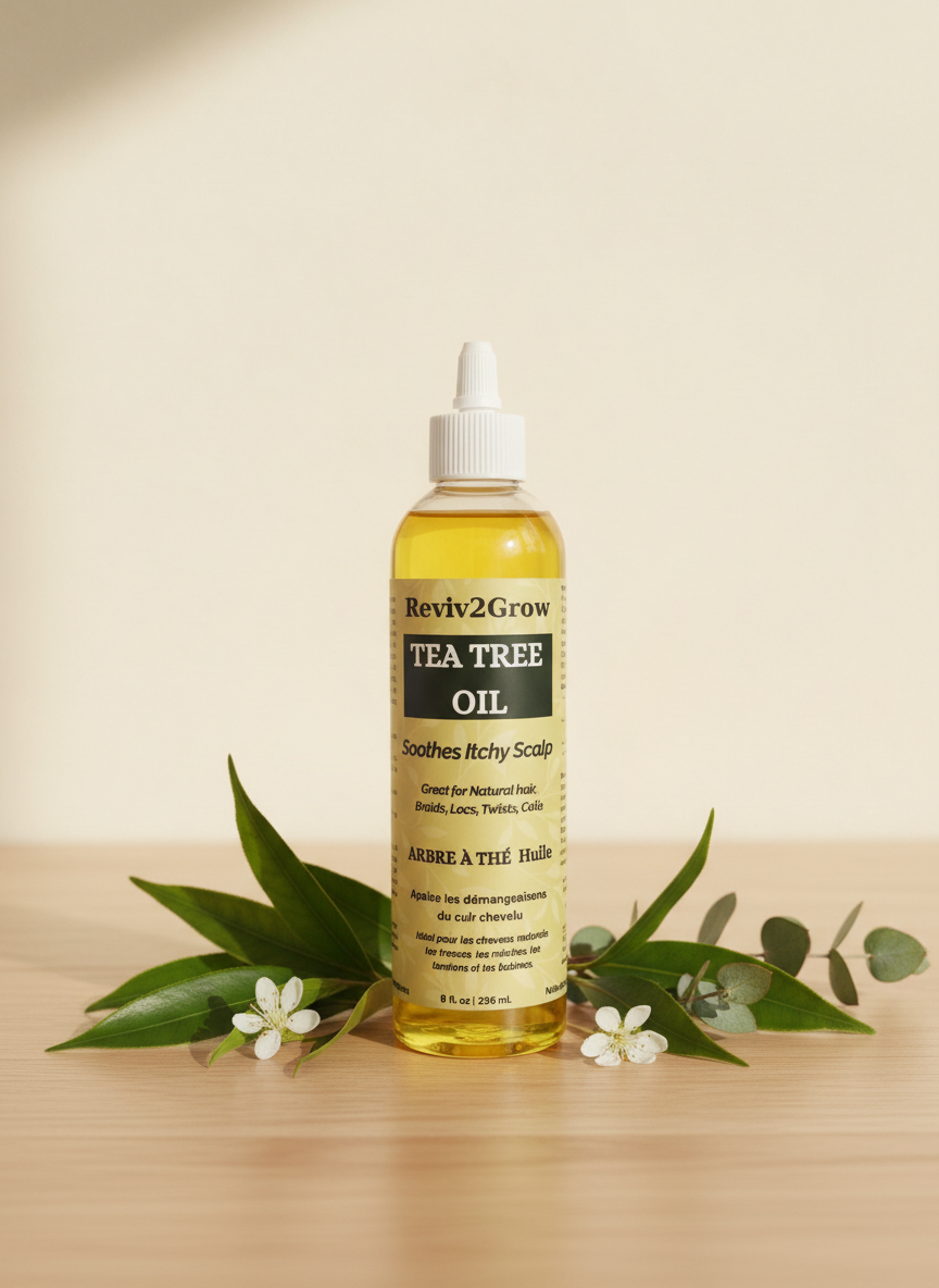 Bottle of Reviv2Grow Tea Tree Oil on a wooden surface with green leaves and flowers.