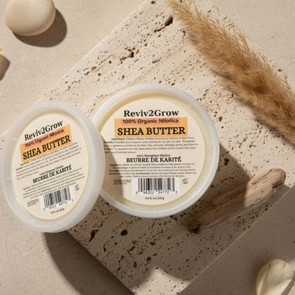 Two containers of Reviv2Grow Shea Butter on a textured surface with decorative elements.