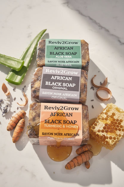 Three bars of African Black Soap from Reviv2Glow on a marble surface.