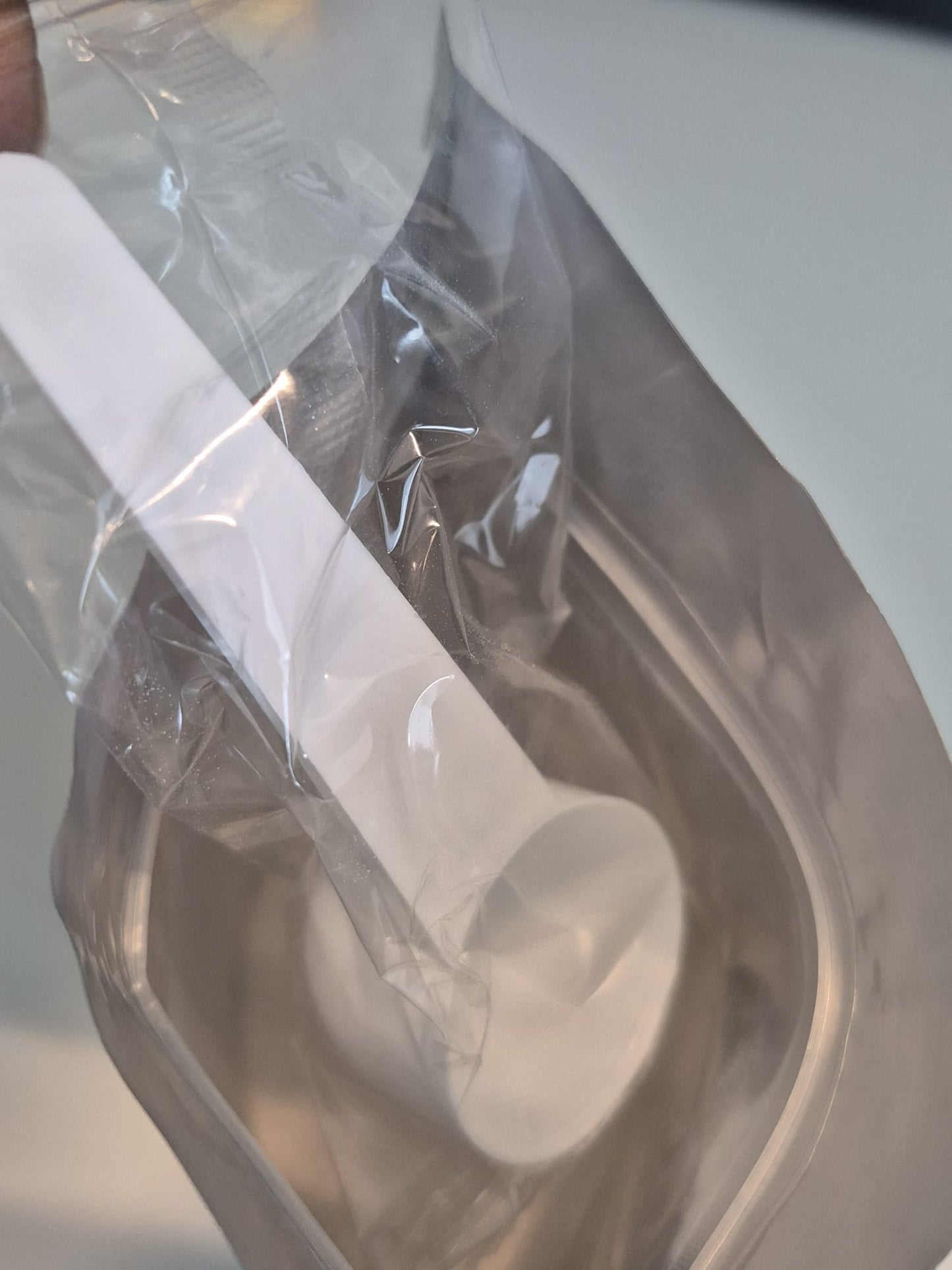 White plastic spoon in a clear plastic bag on a white background