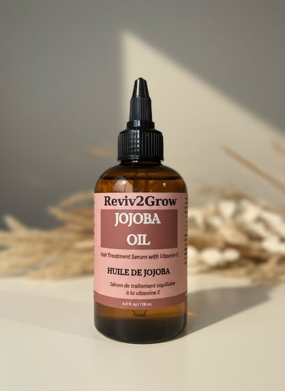 Reviv2Grow Jojoba Oil bottle with a pink label on a neutral background